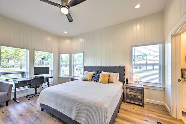 bedroom with wood walls, ceiling fan, and light hardwood / wood-style flooring