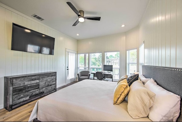 bedroom featuring wooden walls, ceiling fan, and light hardwood / wood-style flooring