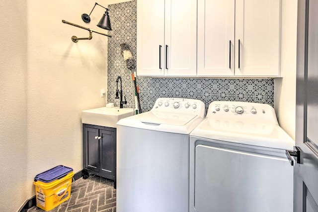 clothes washing area featuring sink, cabinets, and washing machine and clothes dryer