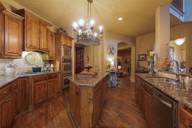 kitchen featuring dark wood-type flooring, sink, hanging light fixtures, and appliances with stainless steel finishes