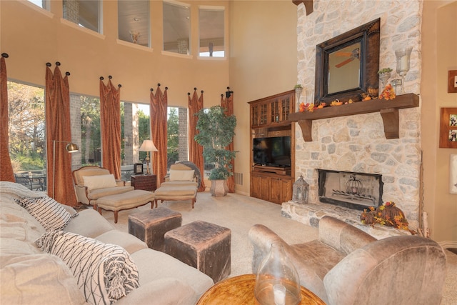 carpeted living room with a stone fireplace and a towering ceiling