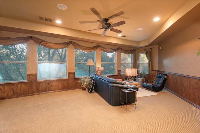 carpeted living room with ceiling fan and wooden walls