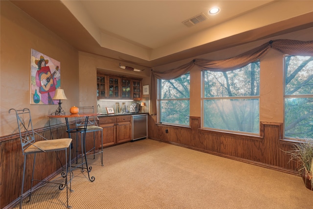 bar featuring wooden walls, light colored carpet, and stainless steel dishwasher