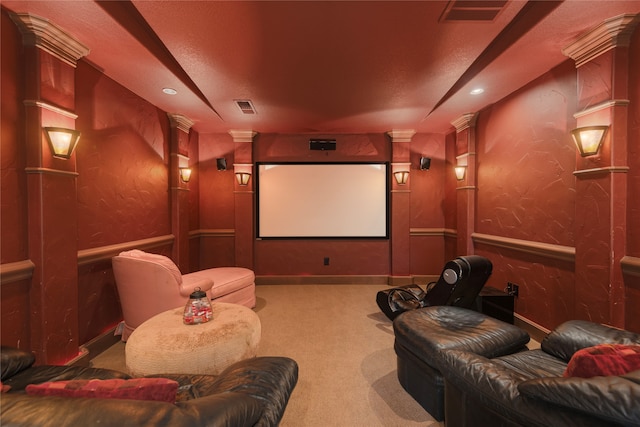 carpeted home theater with decorative columns and a textured ceiling