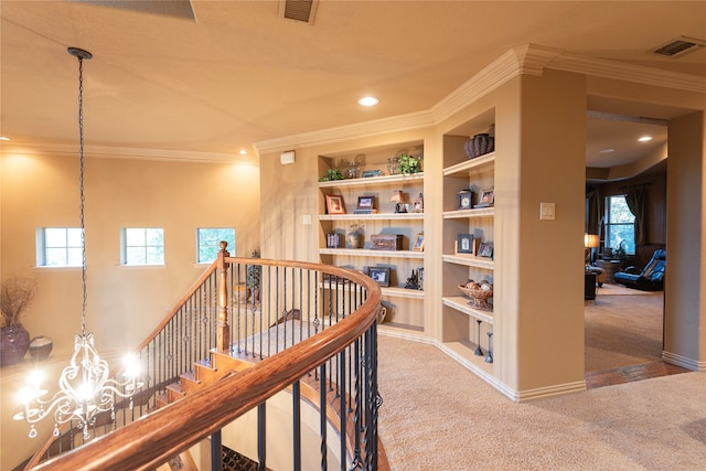 hallway featuring carpet, built in shelves, crown molding, and an inviting chandelier