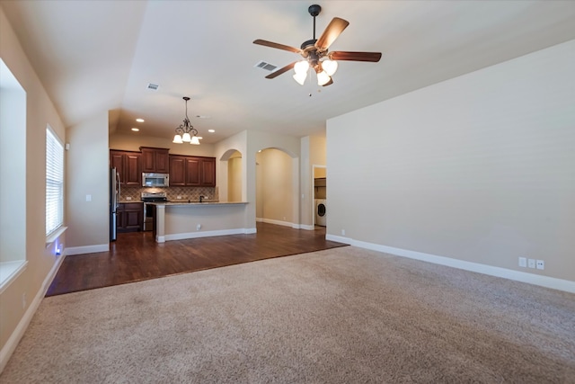 unfurnished living room with dark hardwood / wood-style flooring, washer / dryer, and ceiling fan with notable chandelier