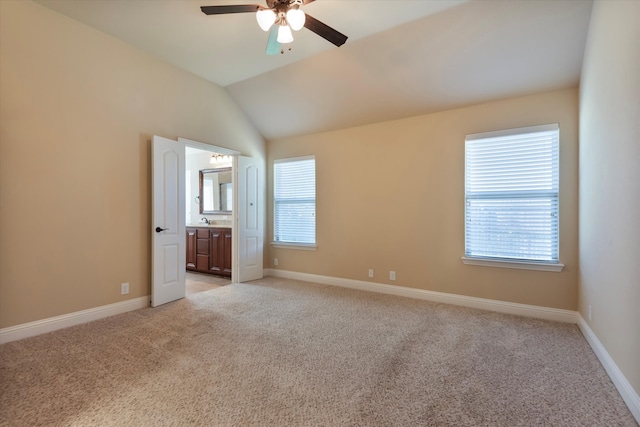 unfurnished bedroom featuring ceiling fan, ensuite bath, light carpet, and lofted ceiling