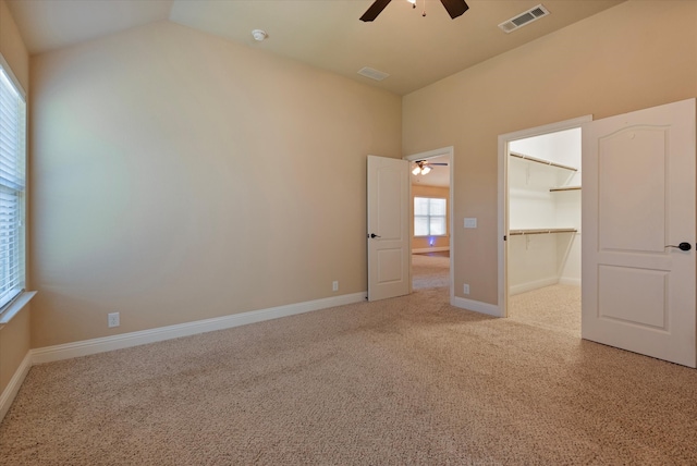 unfurnished bedroom with a closet, carpet, a spacious closet, lofted ceiling, and ceiling fan