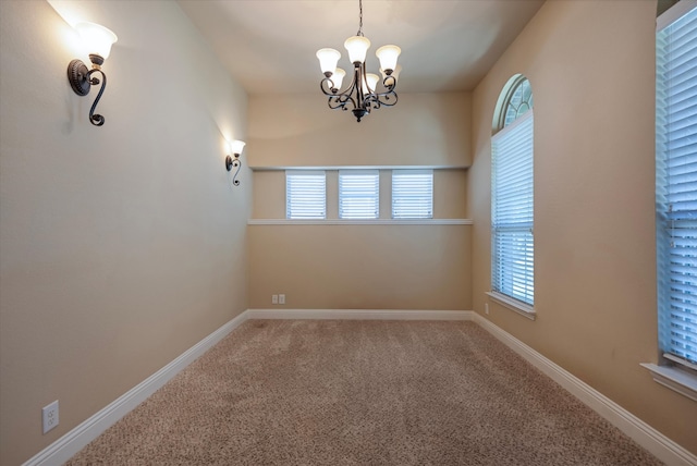 spare room with an inviting chandelier and carpet flooring