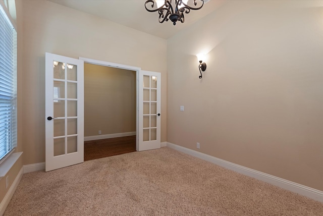 unfurnished room with french doors, carpet floors, and a notable chandelier