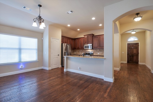 kitchen with stainless steel appliances, light stone countertops, dark hardwood / wood-style floors, vaulted ceiling, and decorative backsplash