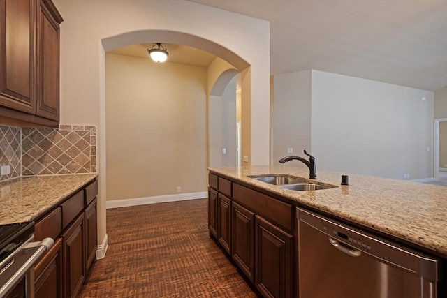 kitchen featuring light stone counters, dark brown cabinets, decorative backsplash, sink, and dishwasher