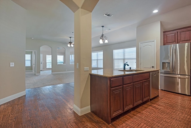 kitchen featuring a wealth of natural light, pendant lighting, appliances with stainless steel finishes, and dark colored carpet