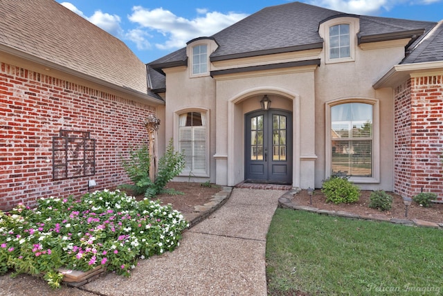 view of exterior entry featuring french doors and a yard