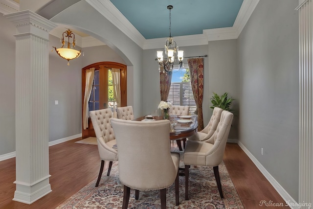 dining area with dark wood-type flooring, an inviting chandelier, a healthy amount of sunlight, and crown molding