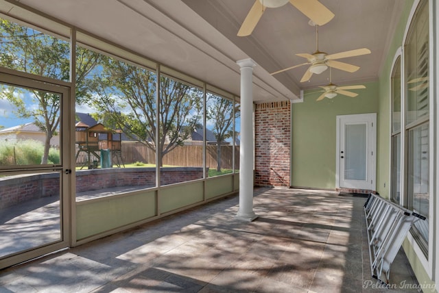 unfurnished sunroom featuring decorative columns and ceiling fan