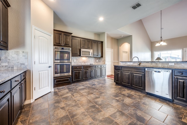 kitchen with stainless steel appliances, lofted ceiling, decorative backsplash, dark brown cabinetry, and sink