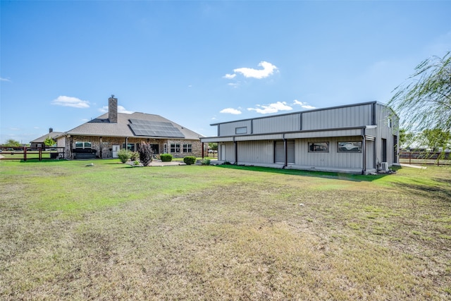 back of property featuring solar panels and a lawn