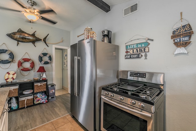 kitchen featuring stainless steel appliances, beamed ceiling, light tile patterned floors, and ceiling fan