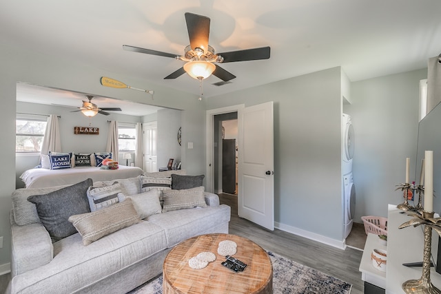 living room featuring hardwood / wood-style floors, ceiling fan, and stacked washer / drying machine