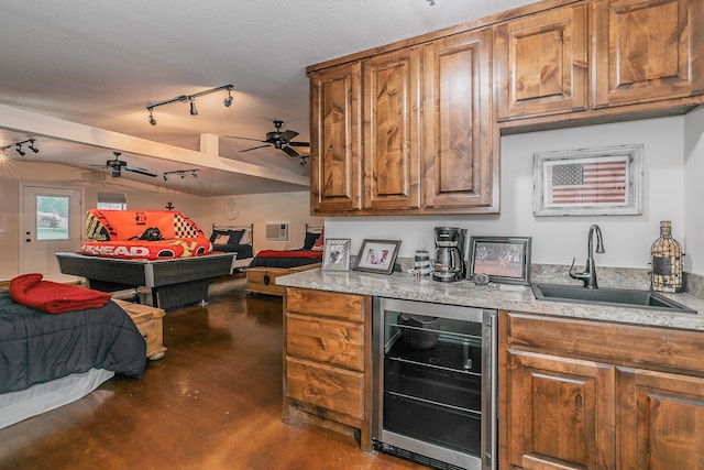 kitchen with wine cooler, sink, ceiling fan, rail lighting, and a textured ceiling