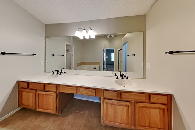 bathroom with tile patterned flooring, a washtub, vanity, and a textured ceiling