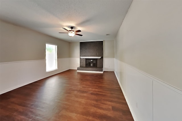 unfurnished living room featuring a fireplace, dark hardwood / wood-style floors, a textured ceiling, and ceiling fan