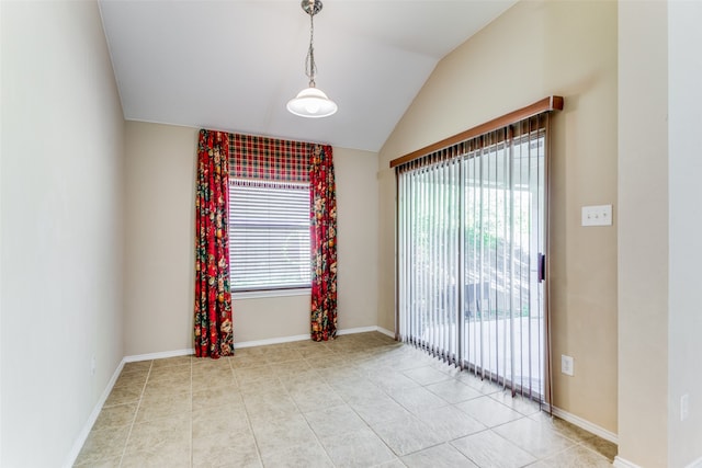 empty room with light tile patterned floors, vaulted ceiling, and a wealth of natural light