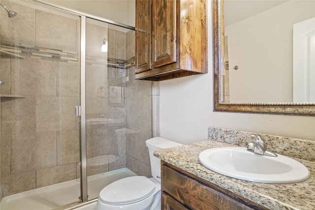 bathroom with toilet, vanity, and a shower with door