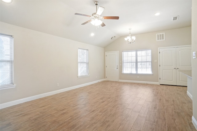 unfurnished room with ceiling fan with notable chandelier, light wood-type flooring, and vaulted ceiling