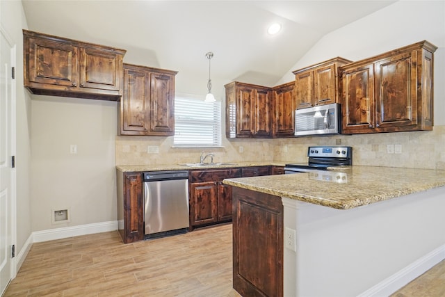 kitchen with kitchen peninsula, lofted ceiling, decorative backsplash, and appliances with stainless steel finishes