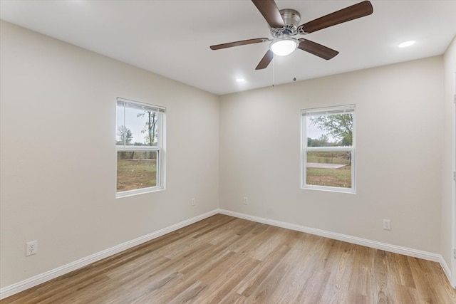 empty room featuring ceiling fan, a healthy amount of sunlight, and light hardwood / wood-style flooring