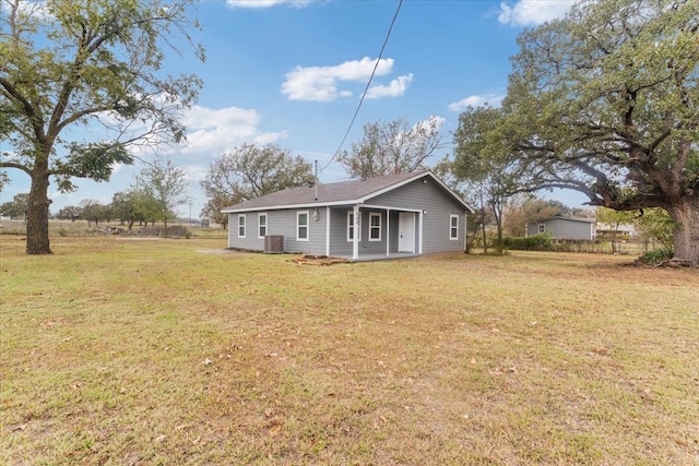 back of property featuring central AC unit and a yard