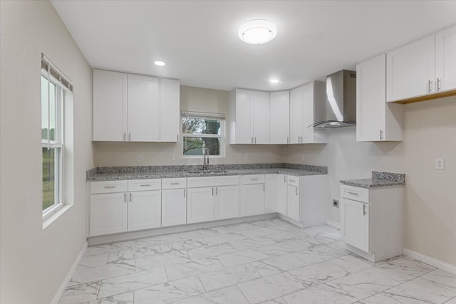 kitchen featuring wall chimney exhaust hood, white cabinetry, plenty of natural light, and sink