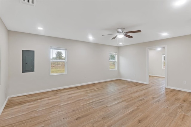 empty room with electric panel, light hardwood / wood-style floors, ceiling fan, and a healthy amount of sunlight