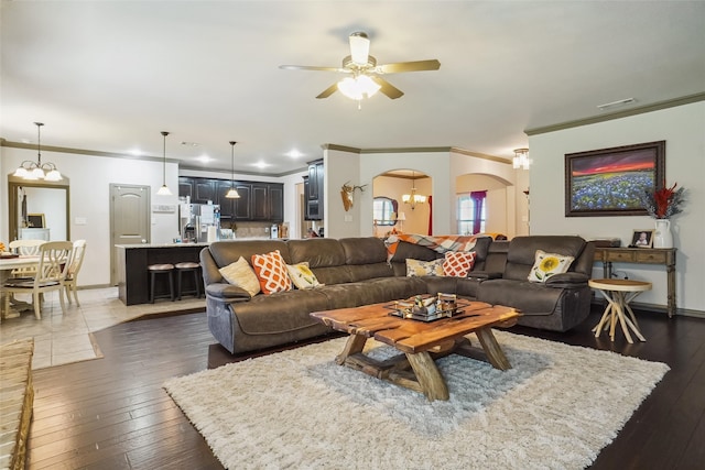 living room featuring ceiling fan with notable chandelier, dark hardwood / wood-style flooring, and ornamental molding