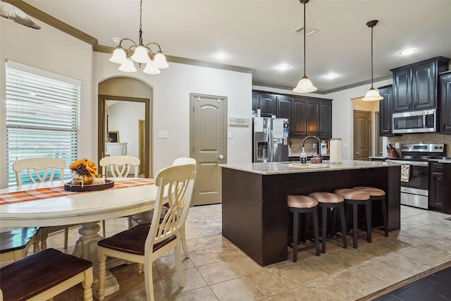 kitchen featuring decorative light fixtures, decorative backsplash, an island with sink, and appliances with stainless steel finishes