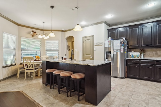 kitchen featuring a center island with sink, ornamental molding, stainless steel refrigerator with ice dispenser, and an inviting chandelier