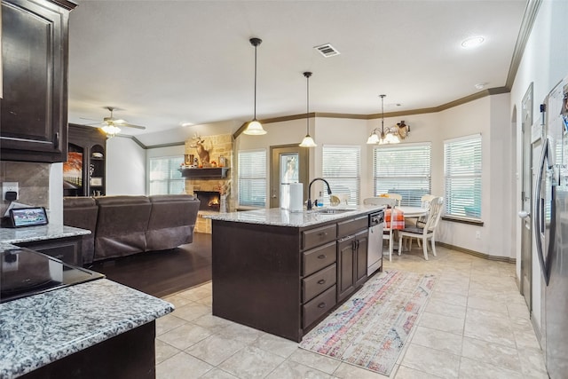 kitchen with a fireplace, ceiling fan with notable chandelier, decorative light fixtures, and a kitchen island with sink