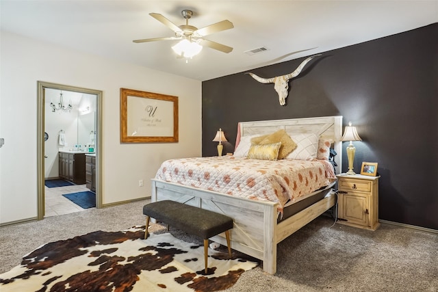 bedroom featuring light carpet, ensuite bathroom, and ceiling fan