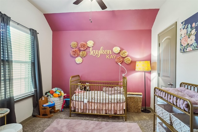 carpeted bedroom with lofted ceiling, ceiling fan, and a crib