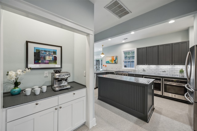 kitchen featuring stainless steel appliances, white cabinets, light tile patterned floors, a kitchen island, and backsplash