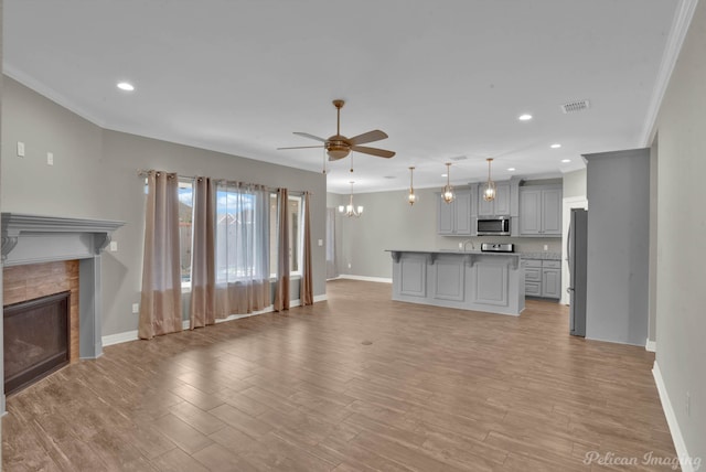 unfurnished living room with a tile fireplace, light hardwood / wood-style floors, ceiling fan, and crown molding