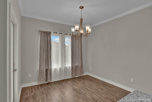 empty room with a chandelier, wood-type flooring, and crown molding