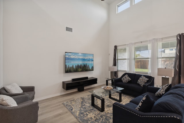 living room featuring light wood-type flooring and a towering ceiling