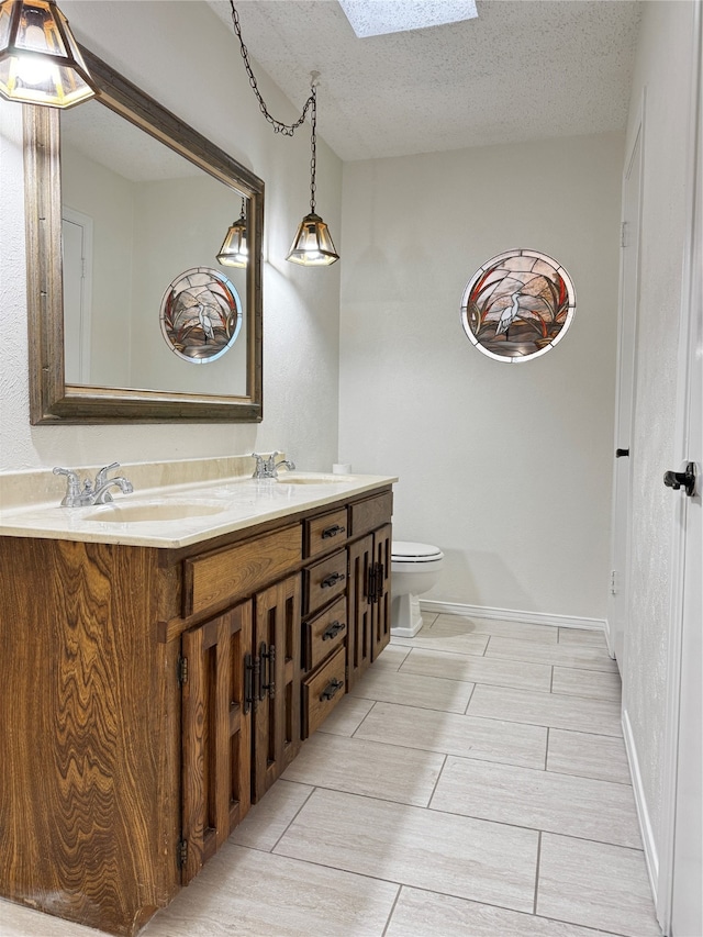 bathroom featuring vanity, toilet, a textured ceiling, and a skylight