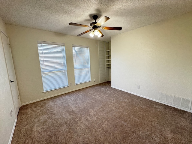 carpeted spare room featuring ceiling fan and a textured ceiling