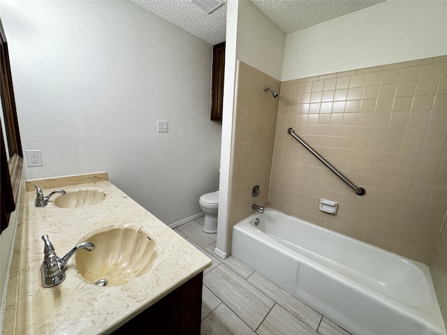 full bathroom featuring vanity, toilet, a textured ceiling, and tiled shower / bath