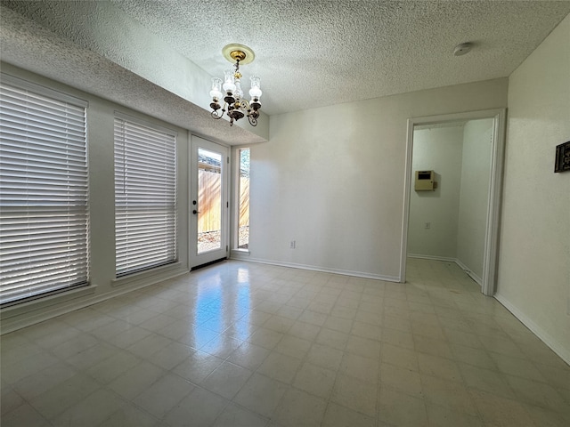 unfurnished room with a notable chandelier and a textured ceiling