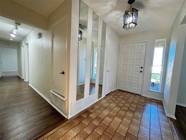 foyer entrance featuring a textured ceiling and dark hardwood / wood-style floors